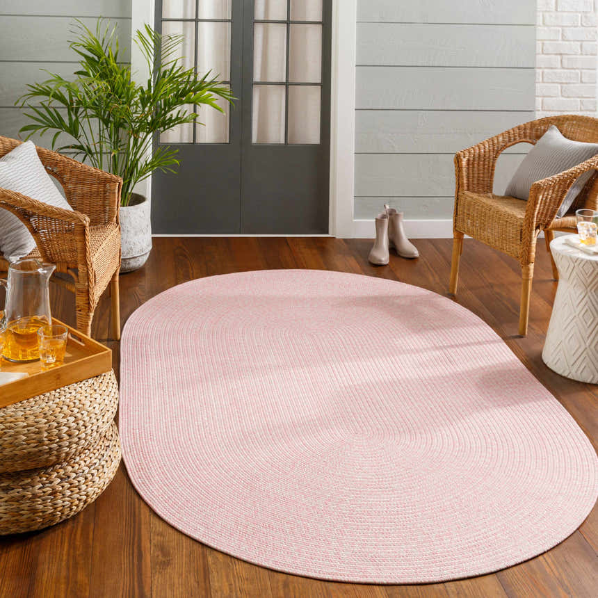 Cozy porch scene with a pink Tycroes Braided Textured Area Rug, wicker chairs, and wood flooring. Roomscene-Oval