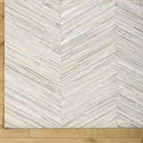 Close-up of the Upland Premium Rug. Hand-crafted hair on hide rug with a brown, cream, and gray chevron pattern. Corner