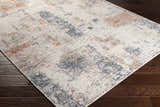 Upminster Area Rug close-up. Abstract design in brick red, charcoal, beige, gray, peach, rust, taupe, and teal on dark wood floor. Corner