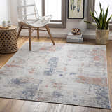 Coastal living room scene with Upminster Area Rug in brick red, charcoal, and beige. White chair, wood floors, and natural light. Roomscene-Rectangle