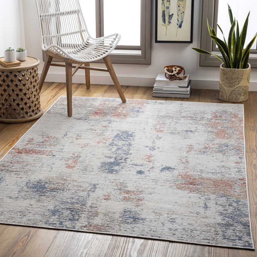 Coastal living room scene with Upminster Area Rug in brick red, charcoal, and beige. White chair, wood floors, and natural light. Roomscene-Rectangle