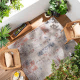 Sunlit living room with woven chairs and Upminster Area Rug in brick red, charcoal, and beige. Roomscene-Rectangle