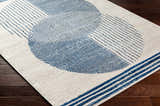 Close up of the Usra Area Rug, featuring a geometric pattern in harbor blue on a natural background. Corner