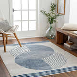 Entryway with Usra Area Rug in harbor blue and white, featuring geometric circles, a white chair, and a wooden bench. Roomscene-Rectangle