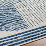 Close-up of the Usra Area Rug showing a geometric pattern in harbor blue and white on a textured surface. Texture