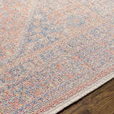 Close-up of the Vahn Area Rug showing its ivory base with dark blue, light pink, and mustard accents. Texture