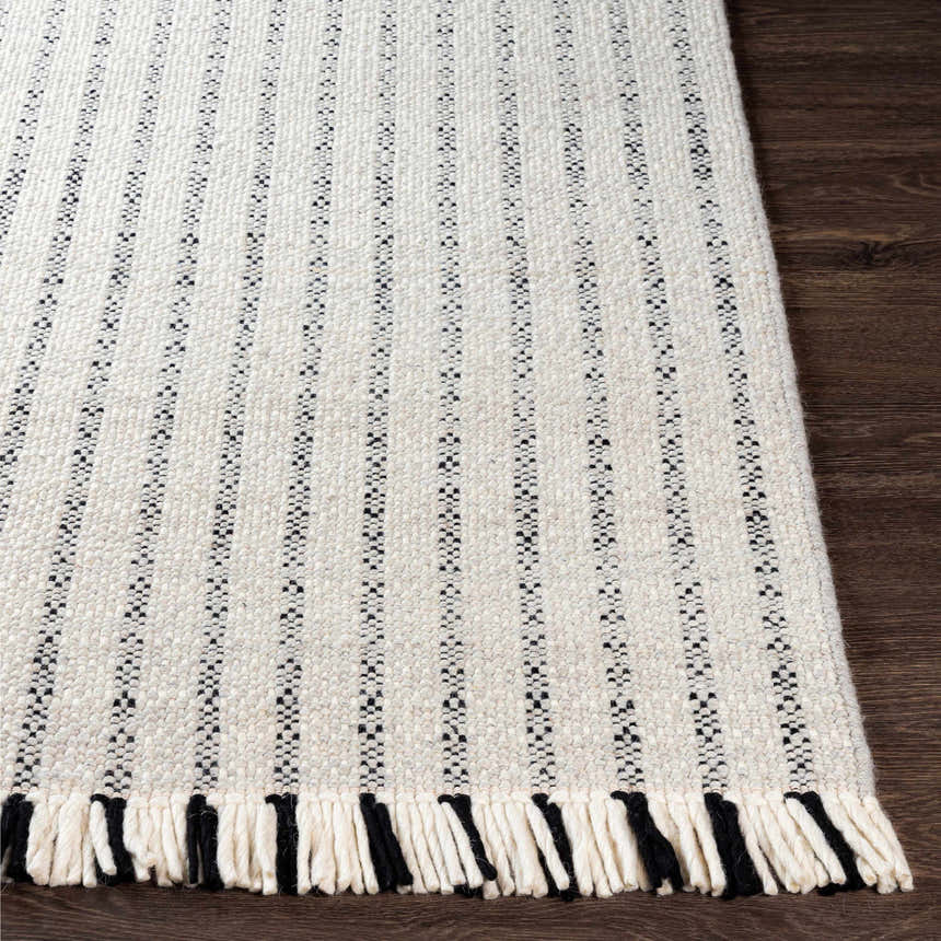 Close-up of the Varennes Area Rug showing its cream and black striped design, wool texture, and fringed edge. Front