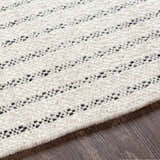 Close-up of the hand woven Varennes Area Rug. Cream wool rug with a black striped pattern and textured detail. Texture