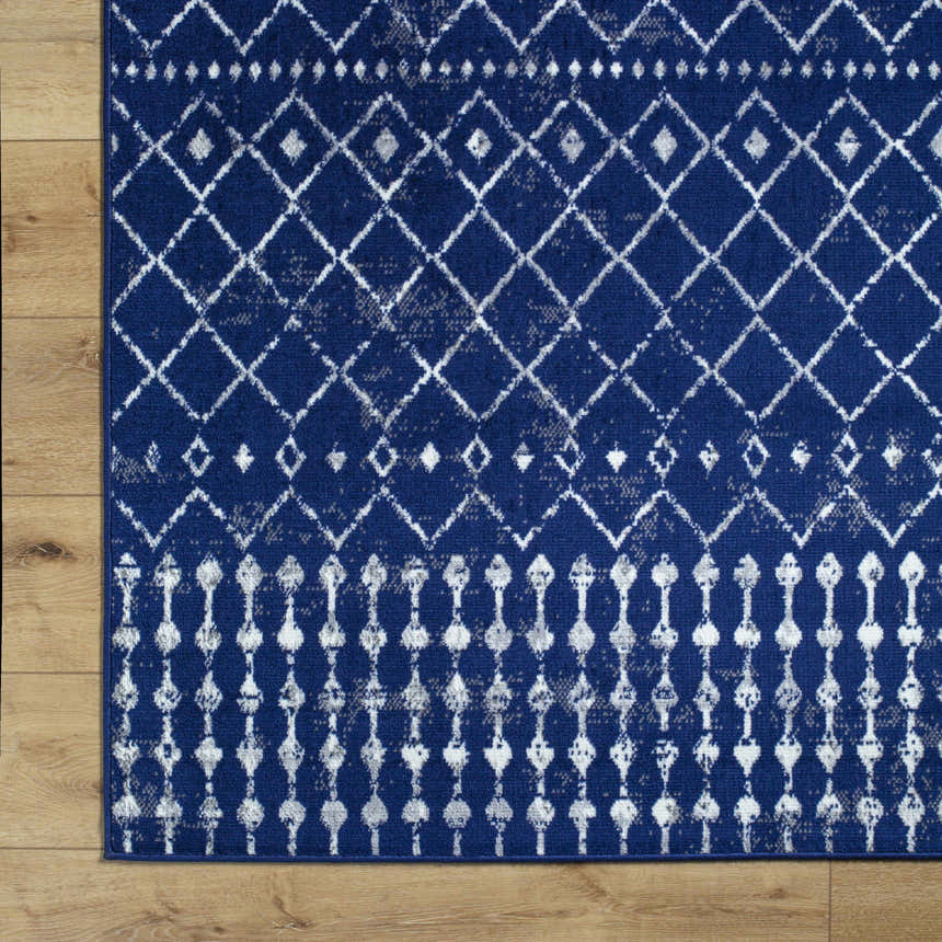 Close-up of the Varun Area Rug, a blue polypropylene rug with a distressed white diamond and geometric pattern. Corner