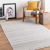 Living room scene with gray Villasis Area Rug, modern chair with yellow pillow, and neutral decor. Roomscene-Rectangle