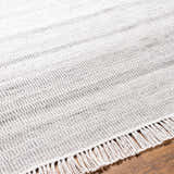 Close up of the hand woven Villasis Area Rug in gray, light beige, and off white with fringe. Texture