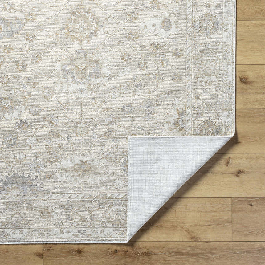 Close-up of the Vaman Luxe Rug showing its light silver and sterling gray traditional floral pattern and machine-woven texture. Fold