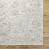 Close-up of the Vaman Luxe Rug in light silver and sterling gray, featuring a traditional floral pattern. Corner