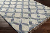 Close-up of the hand woven Walgett Carpet Area Rug. Blue geometric pattern on cream cotton with fringe detail. Corner