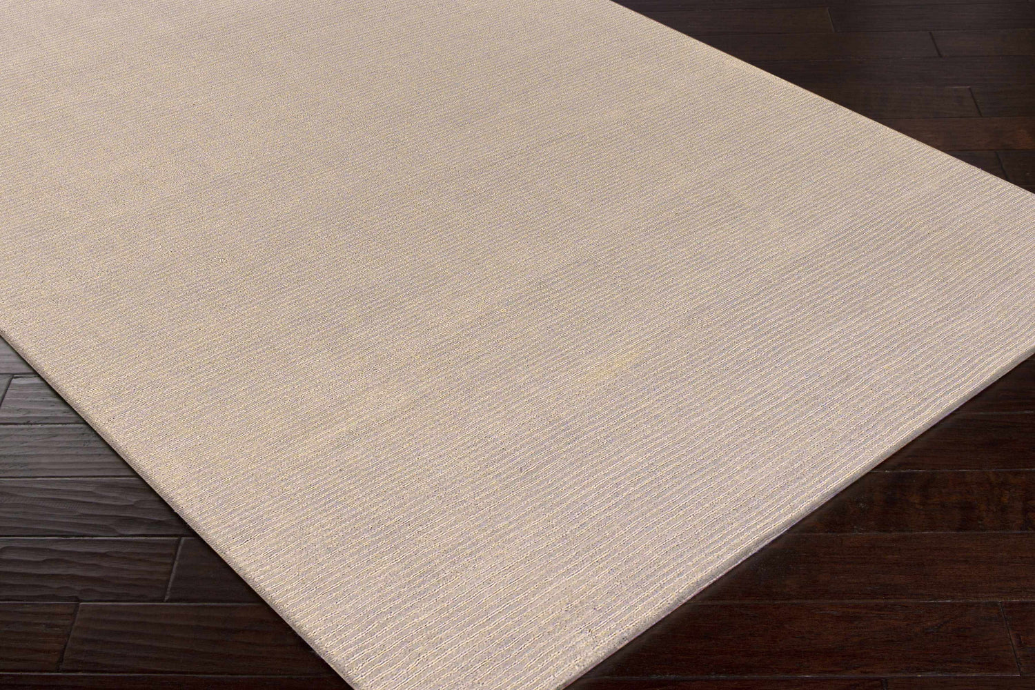 Close-up of the Brockton Solid Tan Rug showing its subtle striped texture and hand-loomed wool construction. Corner