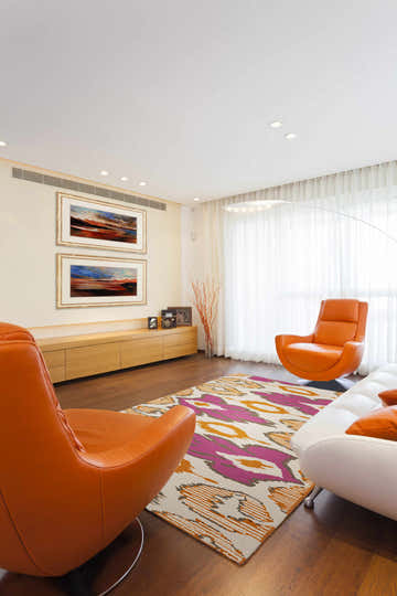 Living room scene with orange chairs and Waymart Area Rug in brown, fuchsia, light beige, and orange. Contemporary style. Roomscene-Rectangle