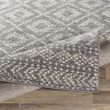 Close-up of the Webb Area Rug, showing its charcoal, gray, and white bohemian pattern and machine woven texture. Fold