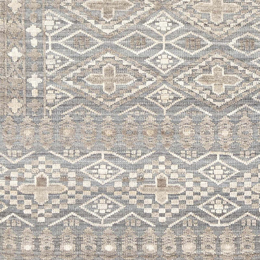 Close-up of the hand-knotted Woodsfield Premium Rug. Beige, brown, and gray geometric diamond and floral pattern. Wool texture. Swatch