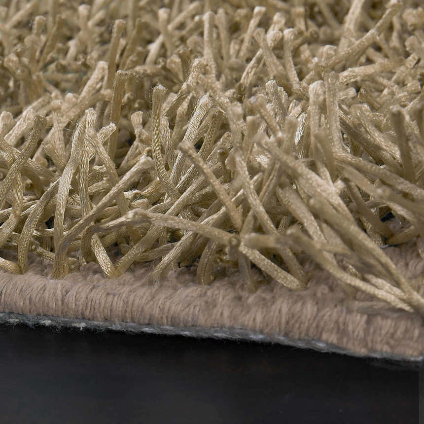 Close-up of the Browder Solid Beige Shag Area Rug showing its thick, soft, polyester pile and hand-woven construction. Texture