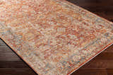 Close-up of the Wetaskiwin Area Rug. Bohemian style with brick red, burnt orange, and blue tones on dark wood floors. Corner
