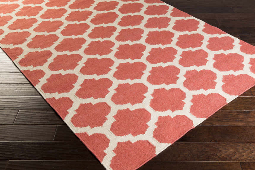 Close-up of the Whitelaw Area Rug. Beige and rose pink geometric pattern, hand woven wool texture. Corner