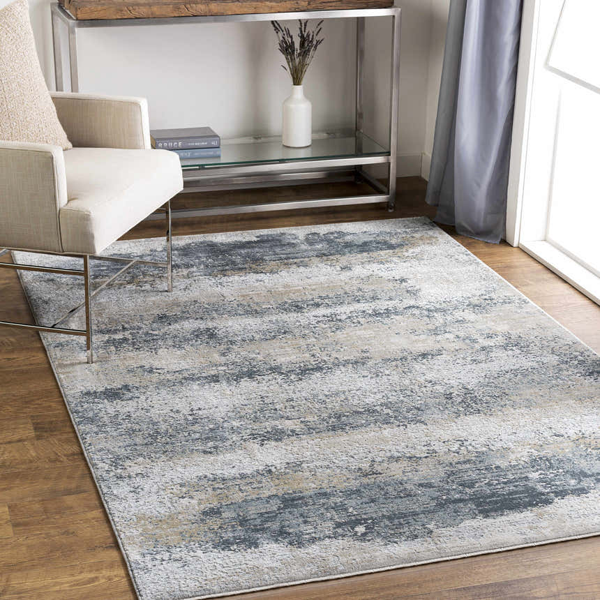 Living room scene with a neutral chair and the Whyalla Misty Thick Luxe Rug in shades of gray, taupe, and white. Roomscene-Rectangle