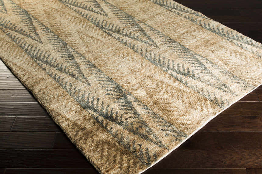 Close up of the Wilburton Jute Carpet showing its hand knotted texture and contemporary design with tan and gray chevron pattern. Corner