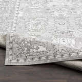 Close-up of the Winstonville Clearance Rug, showcasing a gray and white traditional floral pattern and soft texture. Fold