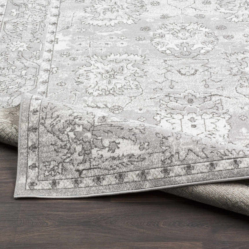 Close-up of the Winstonville Clearance Rug, showcasing a gray and white traditional floral pattern and soft texture. Fold