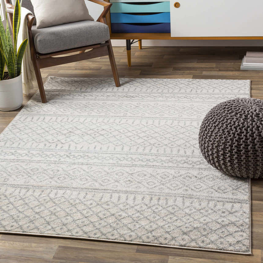 Living room scene with a cream and gray Winston Area Rug, wood chair, and gray pouf. Roomscene-Rectangle
