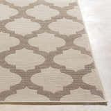 Close-up of the Winterville Area Rug. Beige rug with a dark red quatrefoil pattern. Machine woven texture. Front