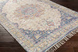 Close-up of Wallburg rug. Hand woven jute rug with light blue, purple, tan, and yellow floral pattern and tassels. Corner