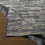 Close-up of the hand-knotted Willmar Premium Rug showing denim, ink blue, and light olive hues and textured wool construction. Front