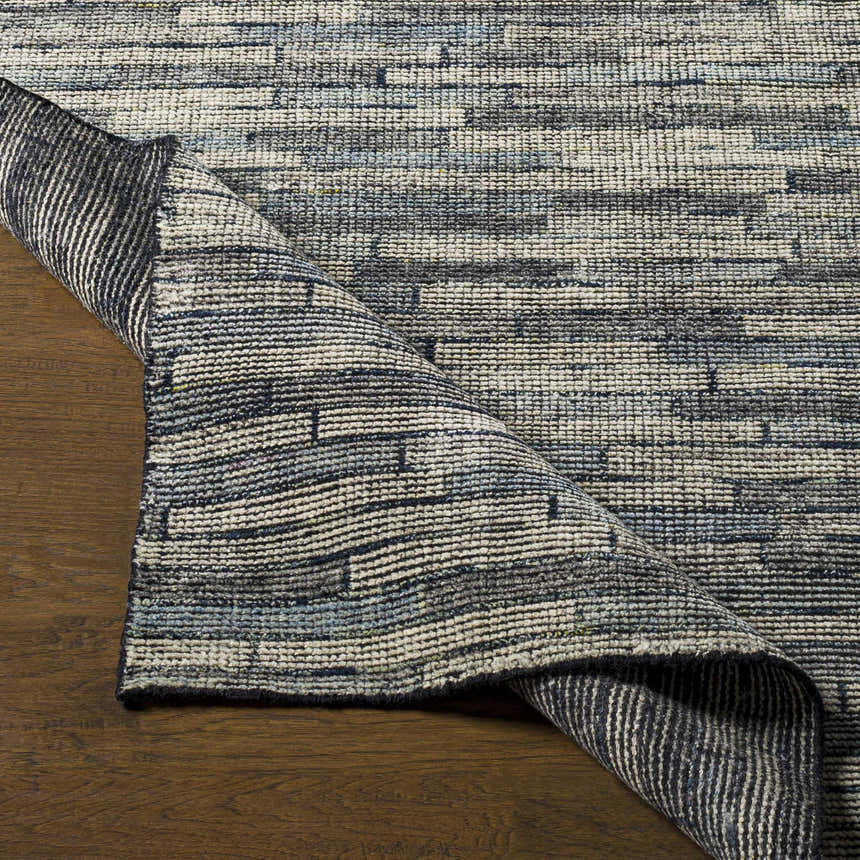 Close-up of the hand-knotted Willmar Premium Rug showing denim, ink blue, and light olive hues and textured wool construction. Front