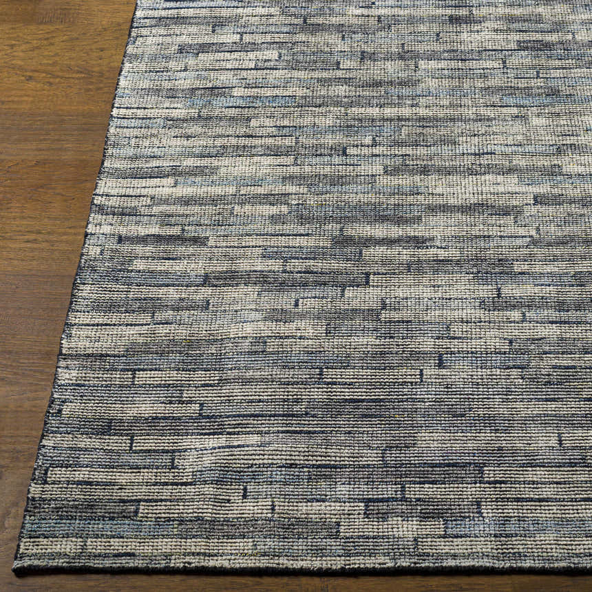 Close-up of the hand-knotted Willmar Premium Rug. Denim, ink blue, and light olive hues create a contemporary striped design. Front