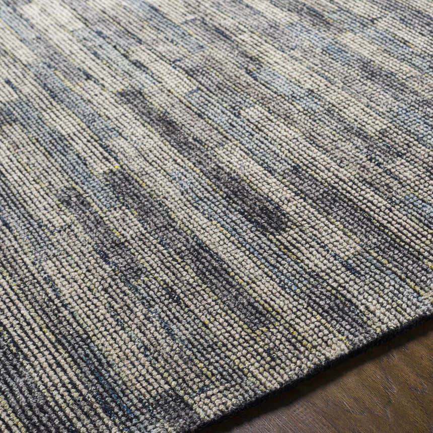 Close-up of the hand-knotted Willmar Premium Rug. Denim, ink blue, light olive, and sage colors in a contemporary linear pattern. Fold