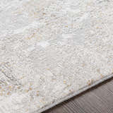 Close-up of the textured Windale Luxe Area Rug. Light gray rug with subtle geometric pattern and hints of mustard. Texture