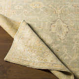 Close-up of the hand-knotted Wooroloo Area Rug. Beige, olive, and tan oriental rug with traditional floral pattern. Fold