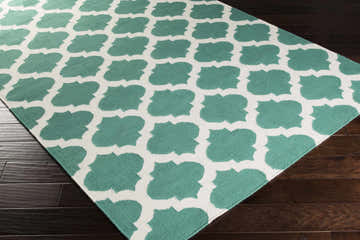 Close-up of Worthington Area Rug. Hand-woven wool rug with a light beige and sage quatrefoil pattern. Corner