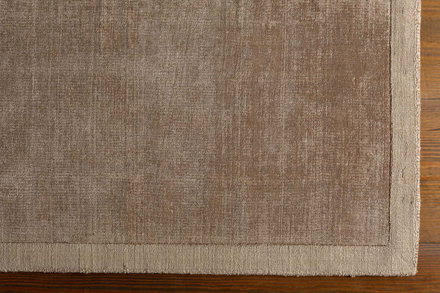 Close-up of the taupe Westbend Area Rug showing its subtle striped pattern and hand-loomed texture on a wood floor. Corner