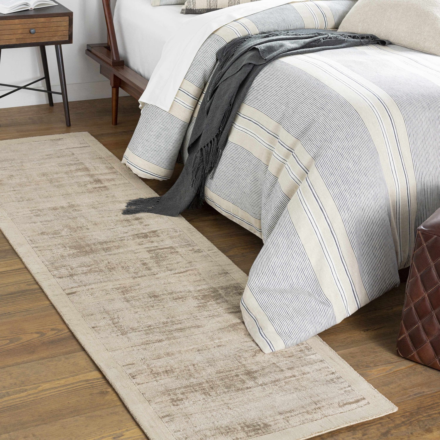 Bedroom scene with taupe Westbend area rug, striped bedding, wood floors, and a cozy, neutral aesthetic. Roomscene-Runner