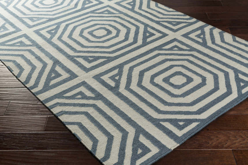 Close-up of the hand woven Westbrook Area Rug. Dark blue and light gray geometric pattern on a wool rug. Corner