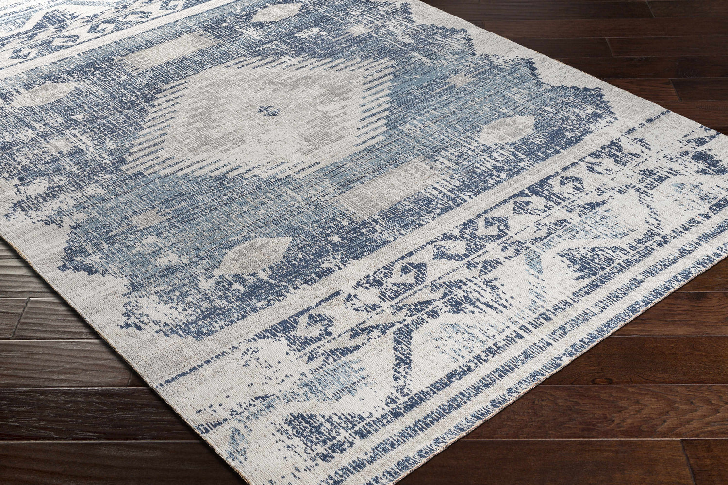 Close-up of the Westmount Denim Aztec Area Rug with cream, denim, and gray colors on dark wood flooring. Corner