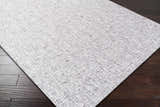Close-up of the Westoning Area Rug showing its light gray, off-white, and charcoal textured design on dark wood floors. Corner