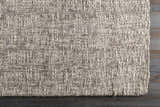 Close-up of the hand-loomed Westoning Area Rug. Neutral colors, textured weave, and rectangular shape on dark wood floor. Corner