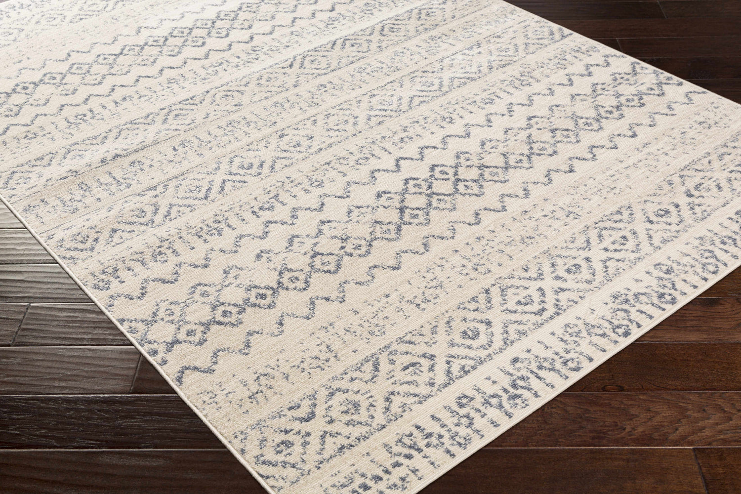 Close-up of the Westborough Beige Area Rug showing a contemporary blue geometric pattern on a cream background. Corner