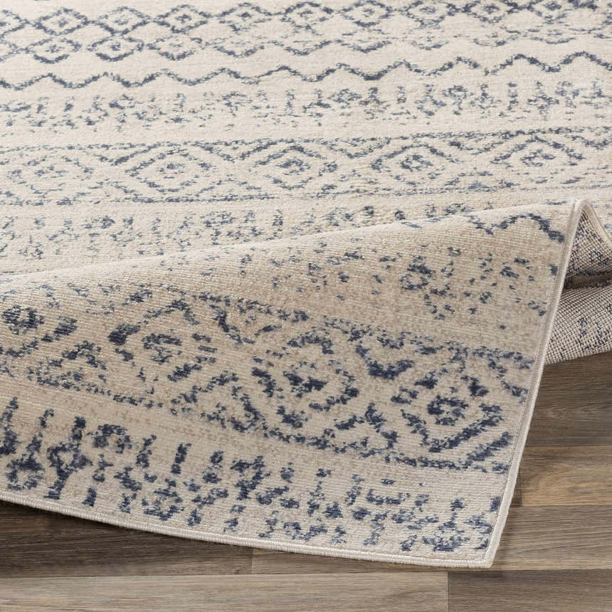Close-up of the Westborough Beige Area Rug showing its contemporary blue geometric pattern and soft, textured weave. Fold