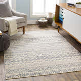 Living room scene with a Westborough Beige Area Rug, gray chair, ottoman, and mid-century modern cabinet. Roomscene-Rectangle