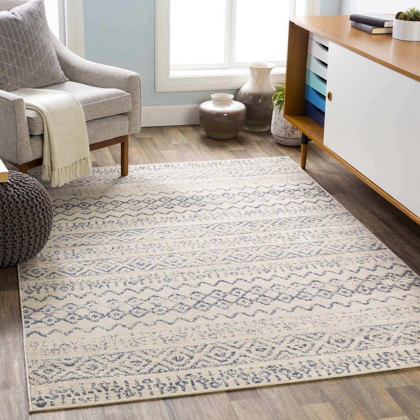 Living room scene with a Westborough Beige Area Rug, gray chair, ottoman, and mid-century modern cabinet. Roomscene-Rectangle