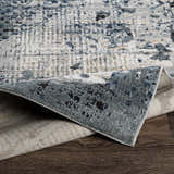 Close-up of the Waterboro Area Rug showing its black, charcoal, and blue contemporary pattern and woven texture. Fold